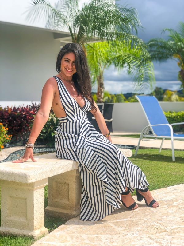 Janice travel. Woman seated on a stone bench in a tropical setting, wearing a striped Topshop dress.