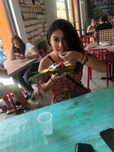 A woman excitedly eating an acai bowl served in a pineapple at OOH Raw Poke and Juice Bar.